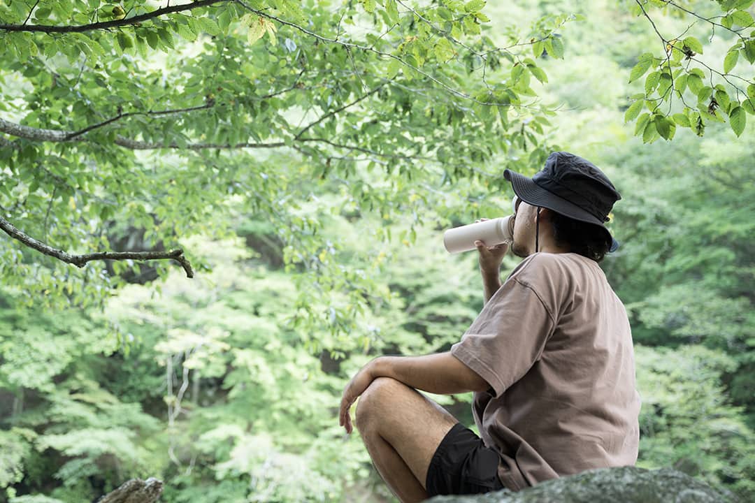 A hiker drinking water during a relaxing break from camping in the mountains.